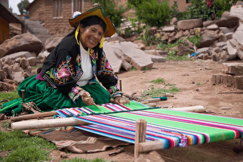 Beautiful local lady from Lake Titicaca with a colorful traditional weaving broom - RESPONSible Travel Peru