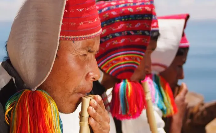 Colorful local men from Taquile island playing traditional instruments. Travel deeper with RESPONSible Travel Peru