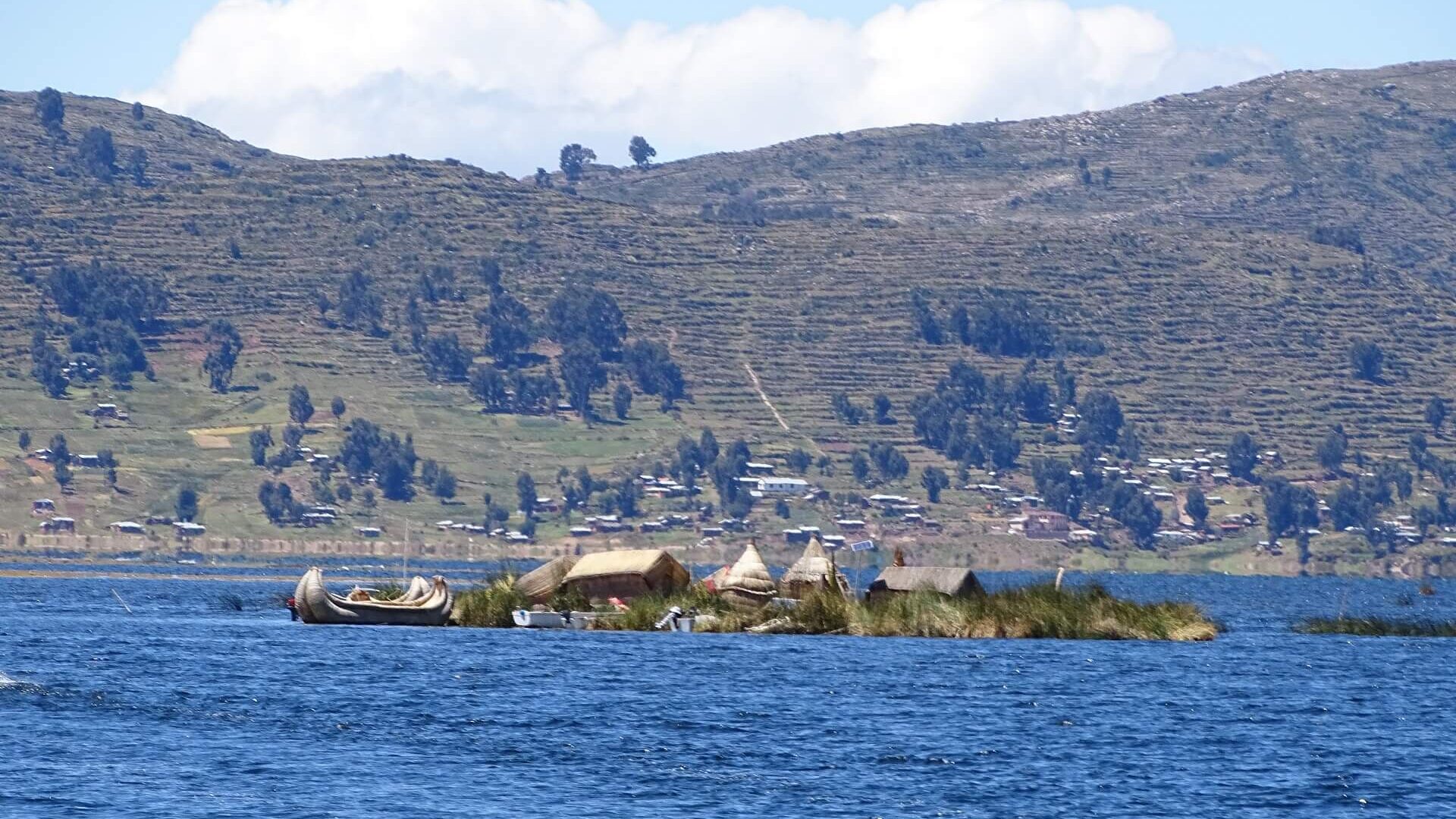 One of the lesser visited Uros Titino floating reed islands with Llachón on the background. Visit Lake Titicaca's hidden gems with RESPONSible Travel Peru!