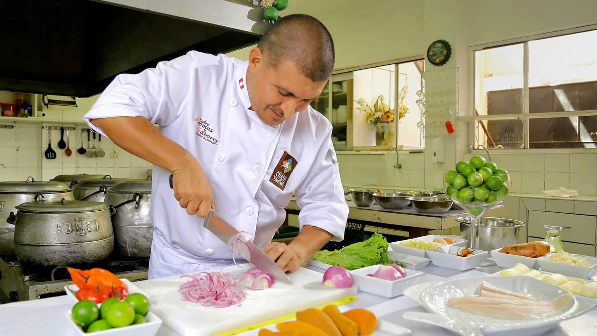 Chef working over cutting board and many ingredients all over the kitchen table | Responsible Travel Peru