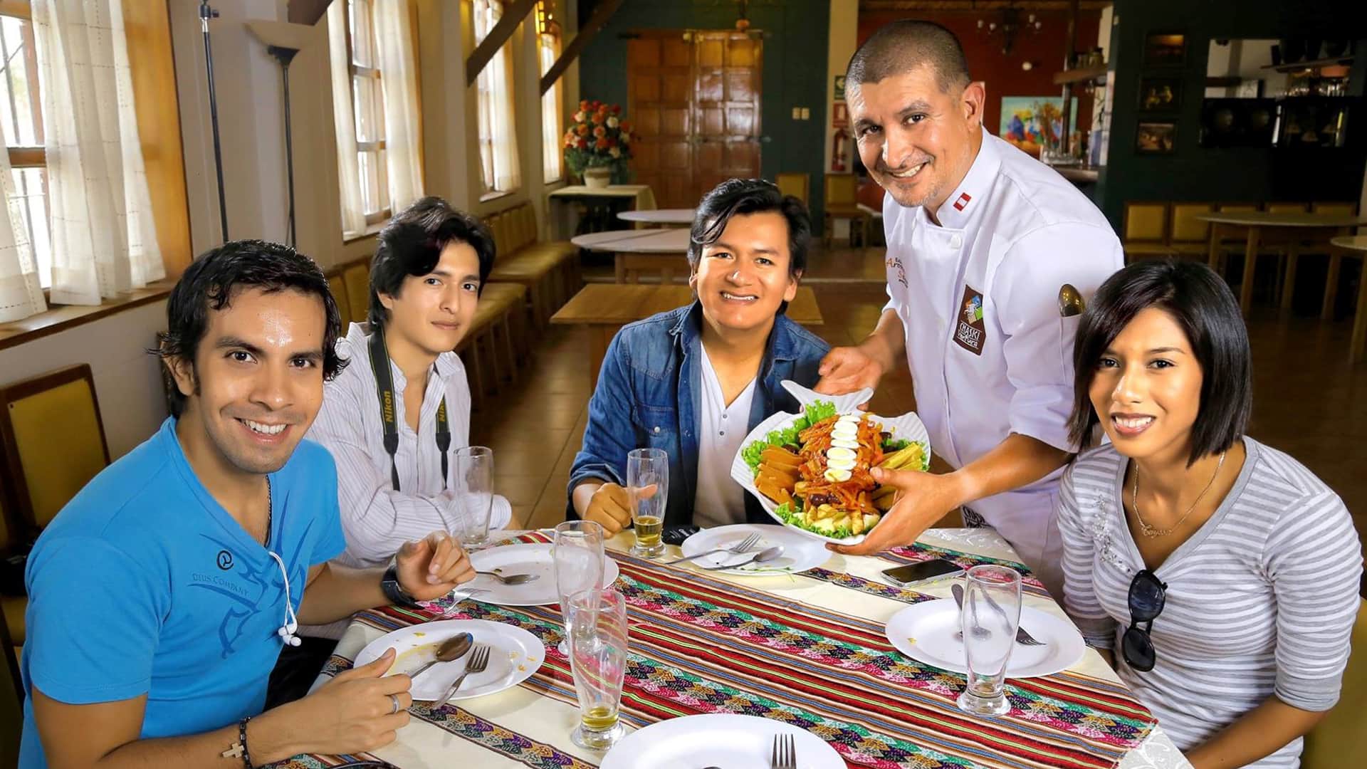 Chef presenting dish to four commensals, all of them smiling | Responsible Travel Peru