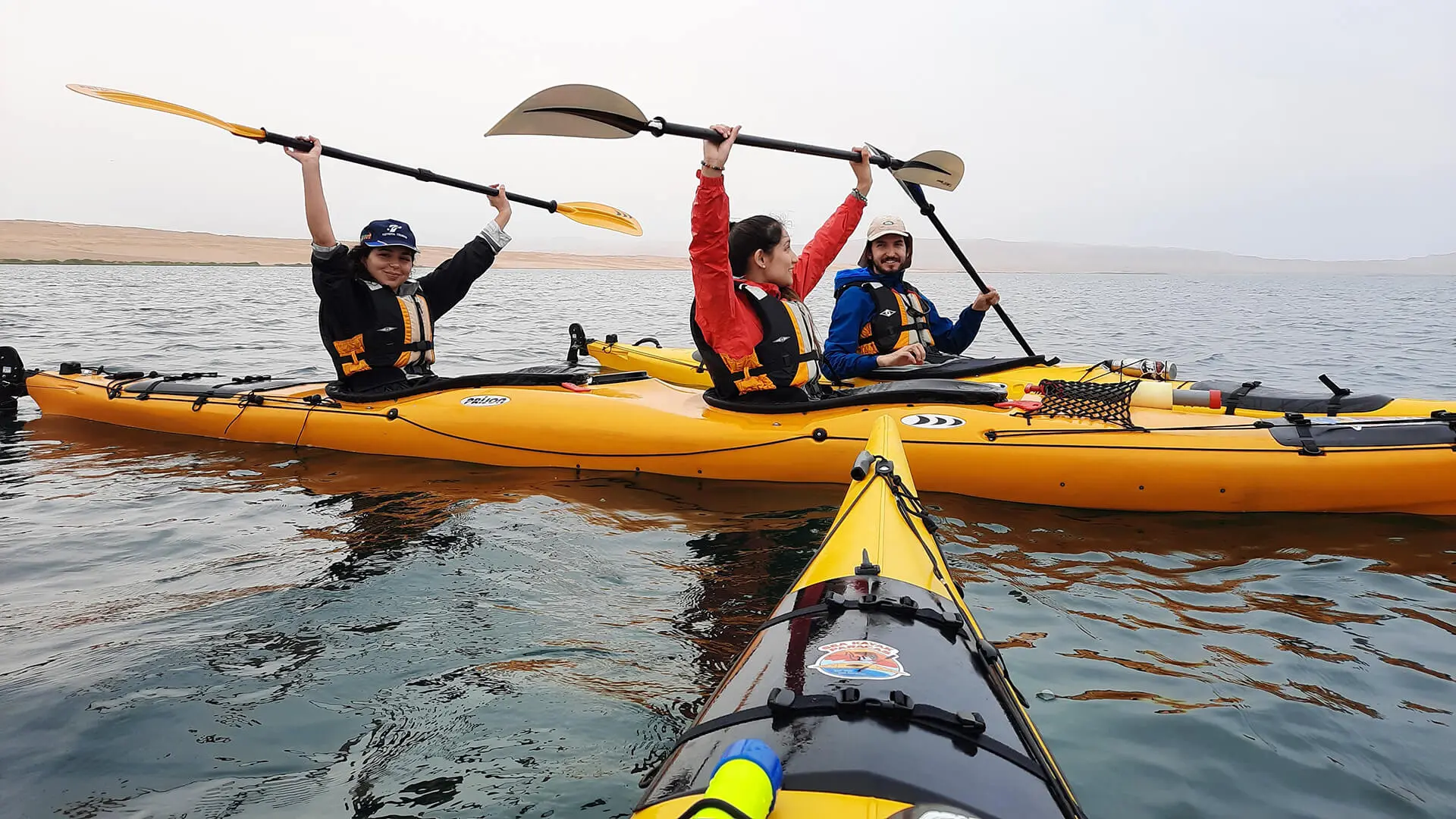 P.O.V. of kayaker of two other kayaks with young passengers saluting with paddles - RESPONSible Travel Peru