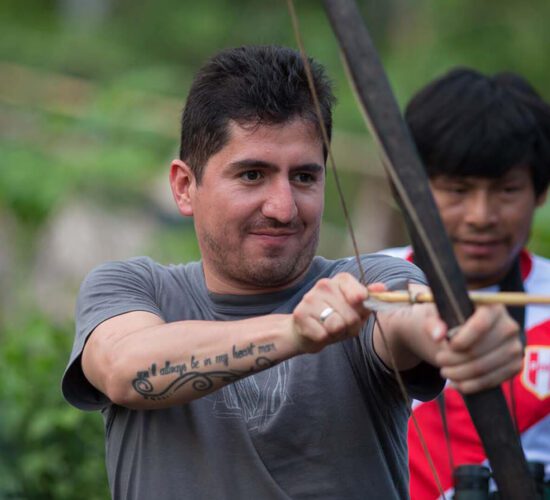 Patrick from Operations Team holding bow and arrow in Shipetiari, a Matsigenka native community in Manu - RESPONSible Travel Peru