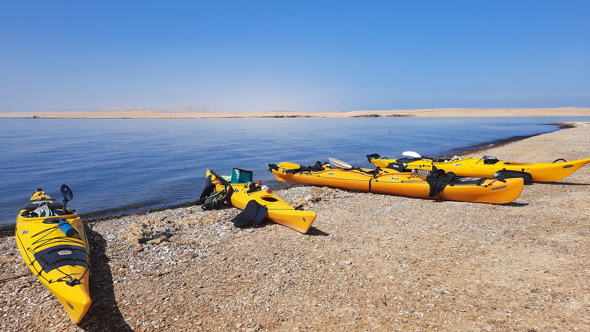Four stationary kayaks and personal belongings at the beach of Paracas - RESPONSible Travel Peru