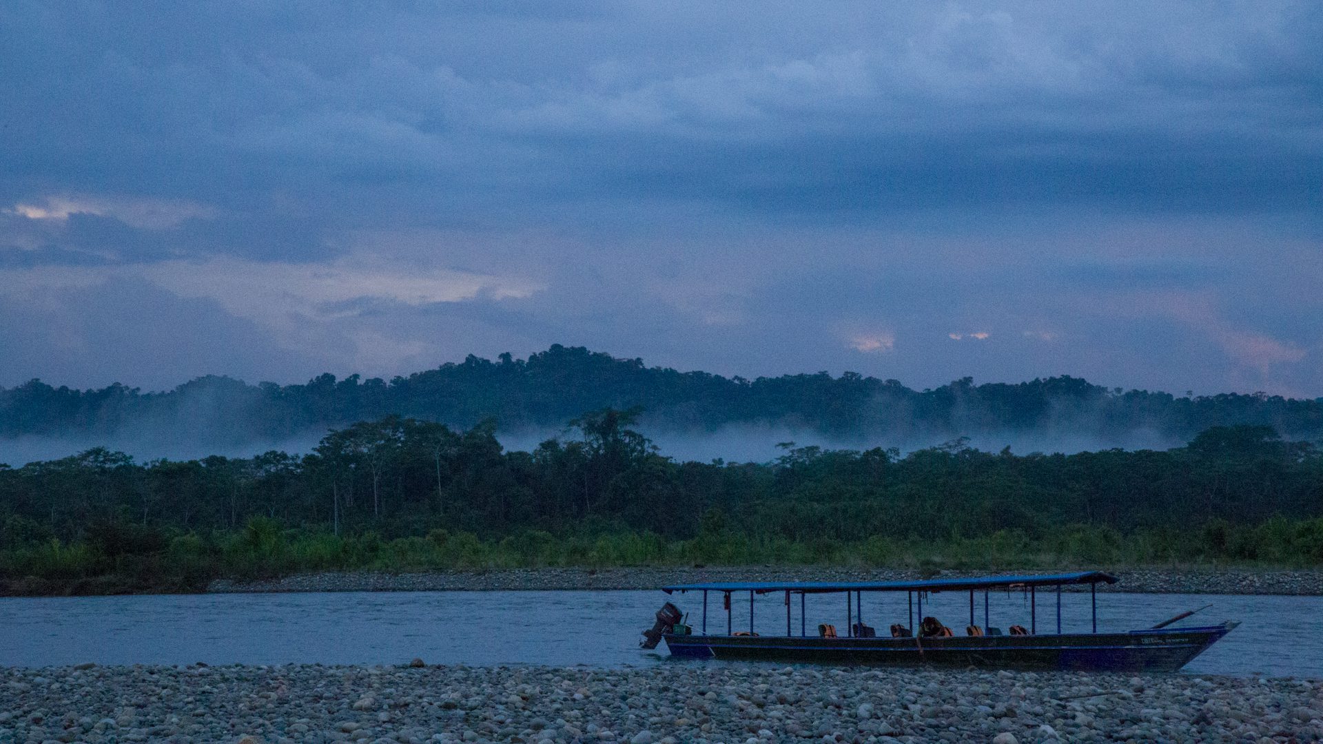 Stationed boat with a background of foggy forest and clouded sky | Responsible Travel Peru