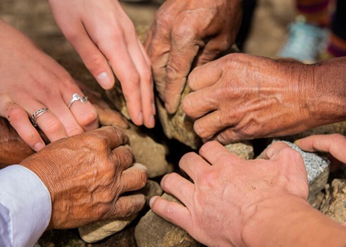 Multiple hands piling rocks for a Pachamanca oven | RESPONSible Travel Peru