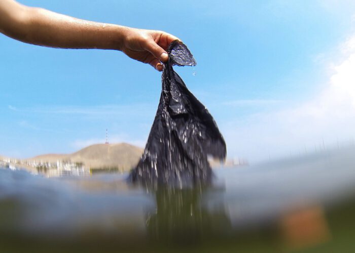 A person removing a black plastic bag from the sea | RESPONSible Travel Peru