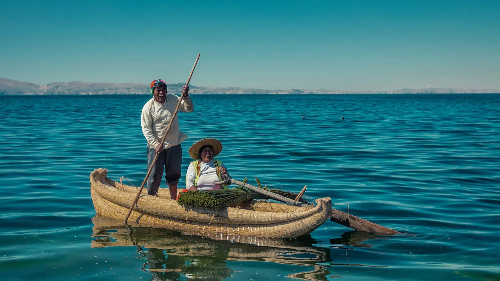 Man and woman over a totora boat after harvesting reeds in Titicaca