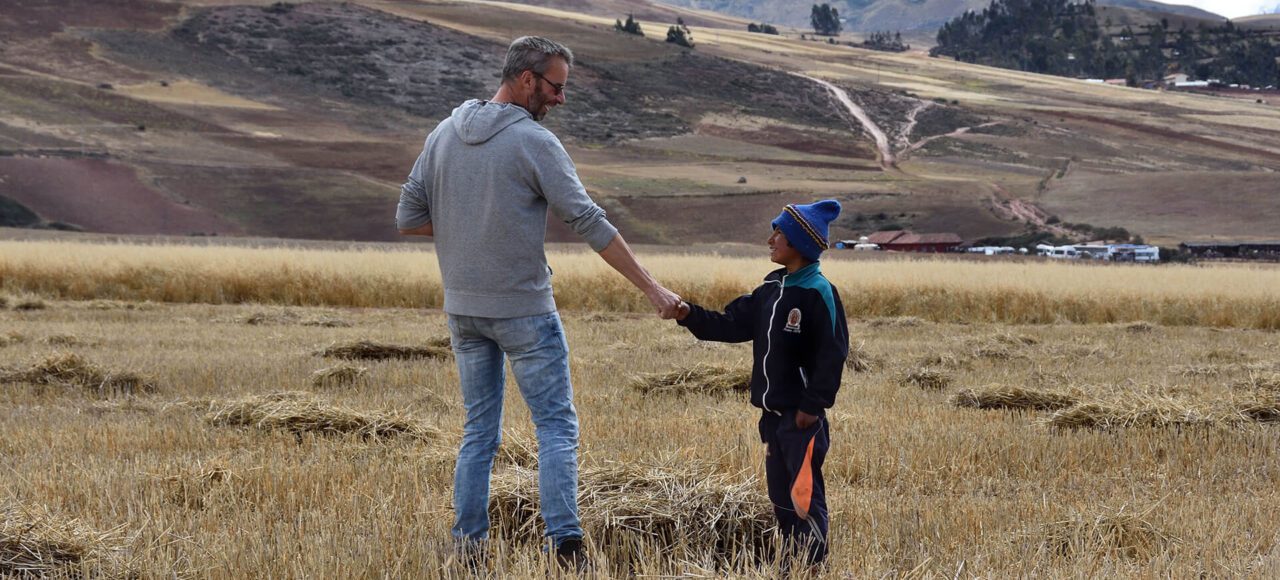 Adult and child shaking hands on Peruvian landscape