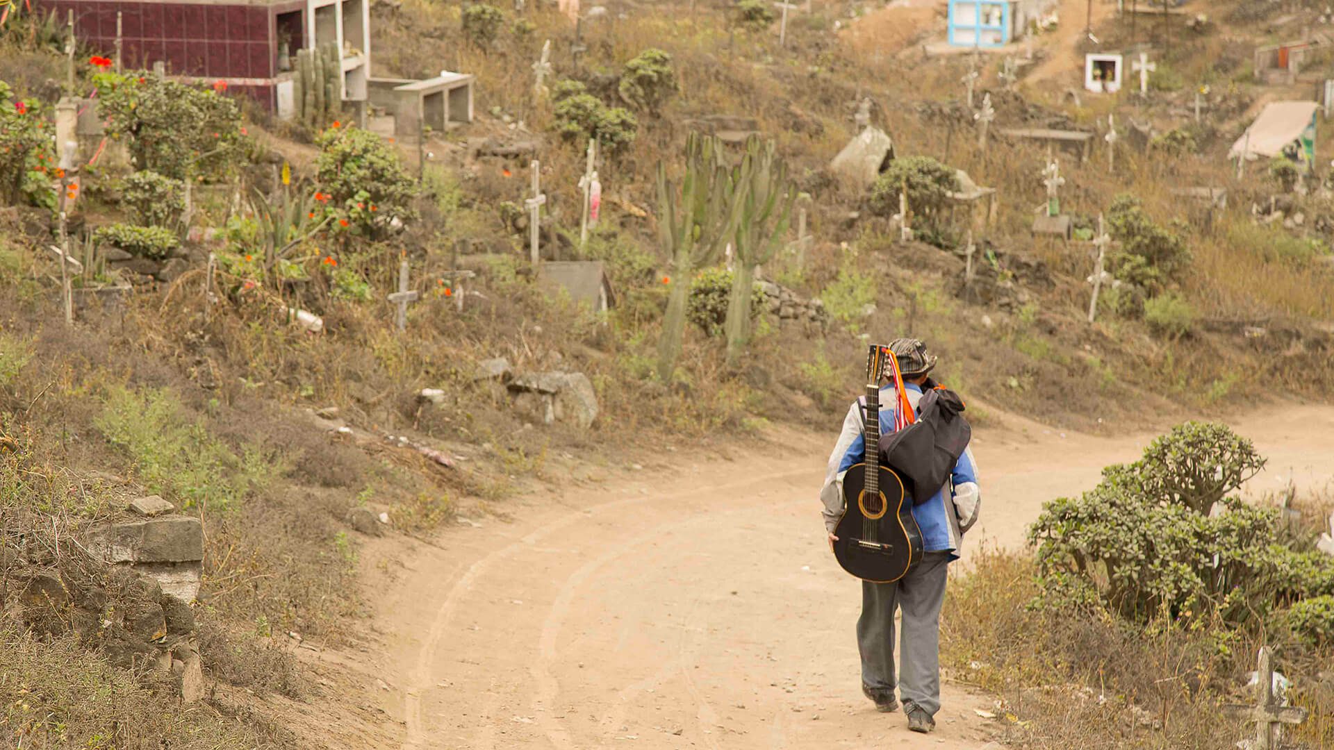 Guitar player walking on a dirt road of the Nueva Esperanza cemetery in Lima | RESPONSible Travel Peru
