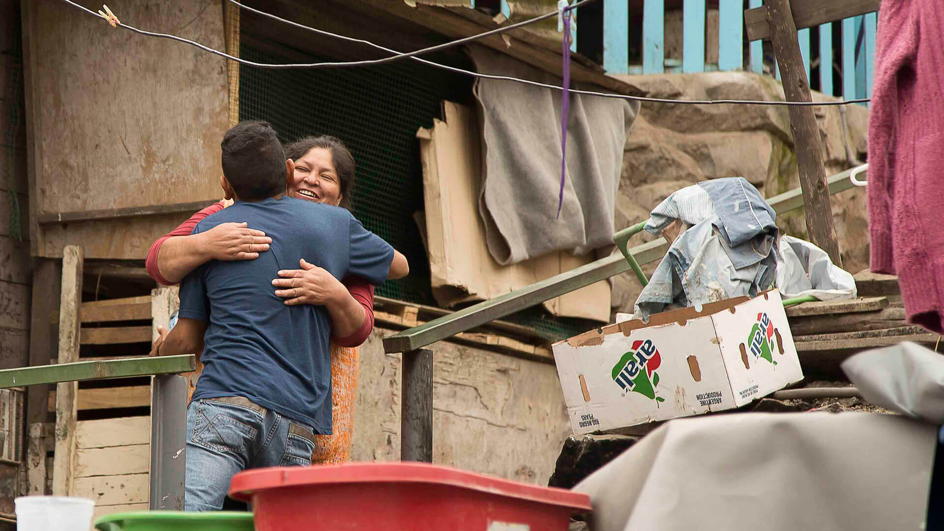 Woman and young man giving each other a hug in the middle of a chaotic scenario of one of Lima slums | RESPONSible Travel Peru
