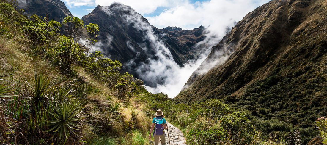 Woman standing on the Inca Trail among mountains, vegetation and clouds | RESPONSible Travel Peru