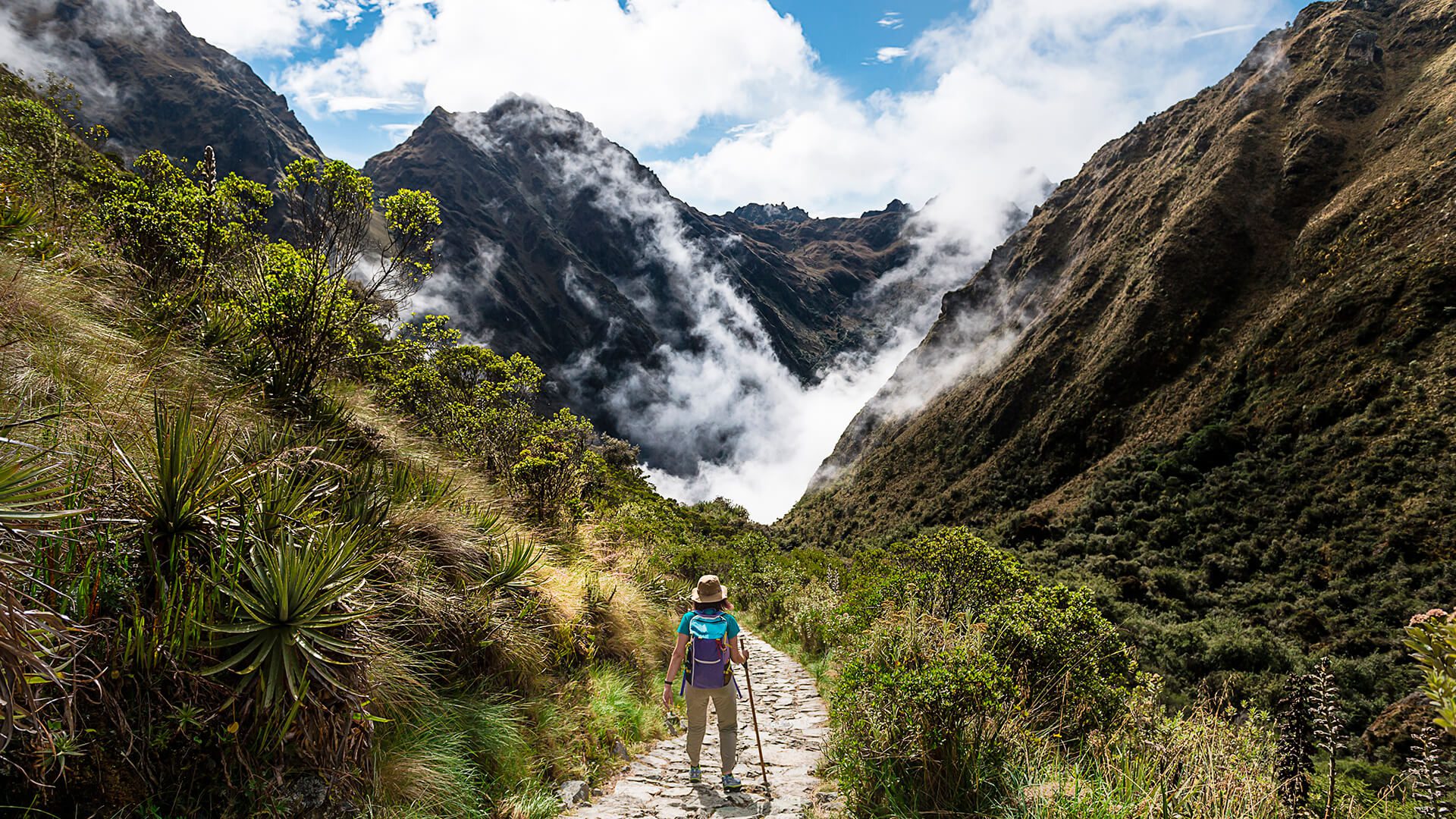 Woman standing on the Inca Trail among mountains, vegetation and clouds | RESPONSible Travel Peru