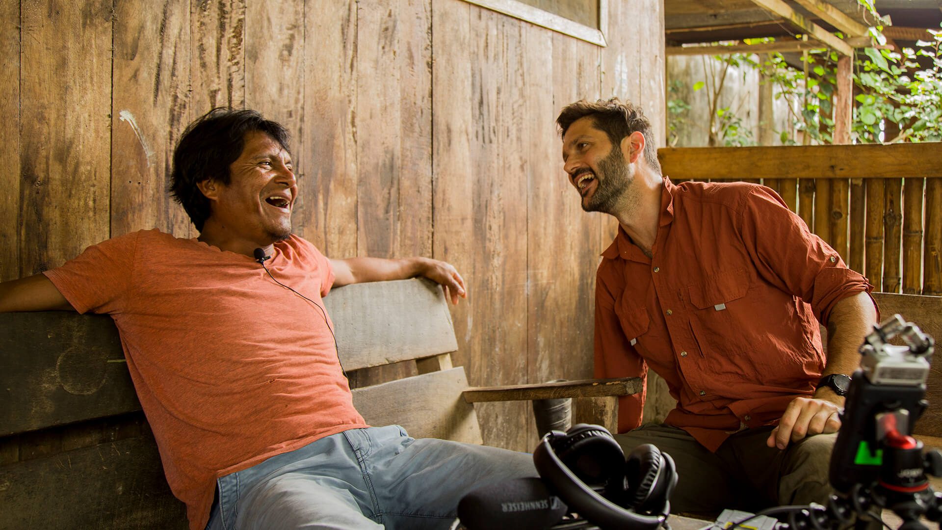 Harakmbut man laughing while being interviewed by documentarist in Shintuya, Manu | Responsible Travel Peru