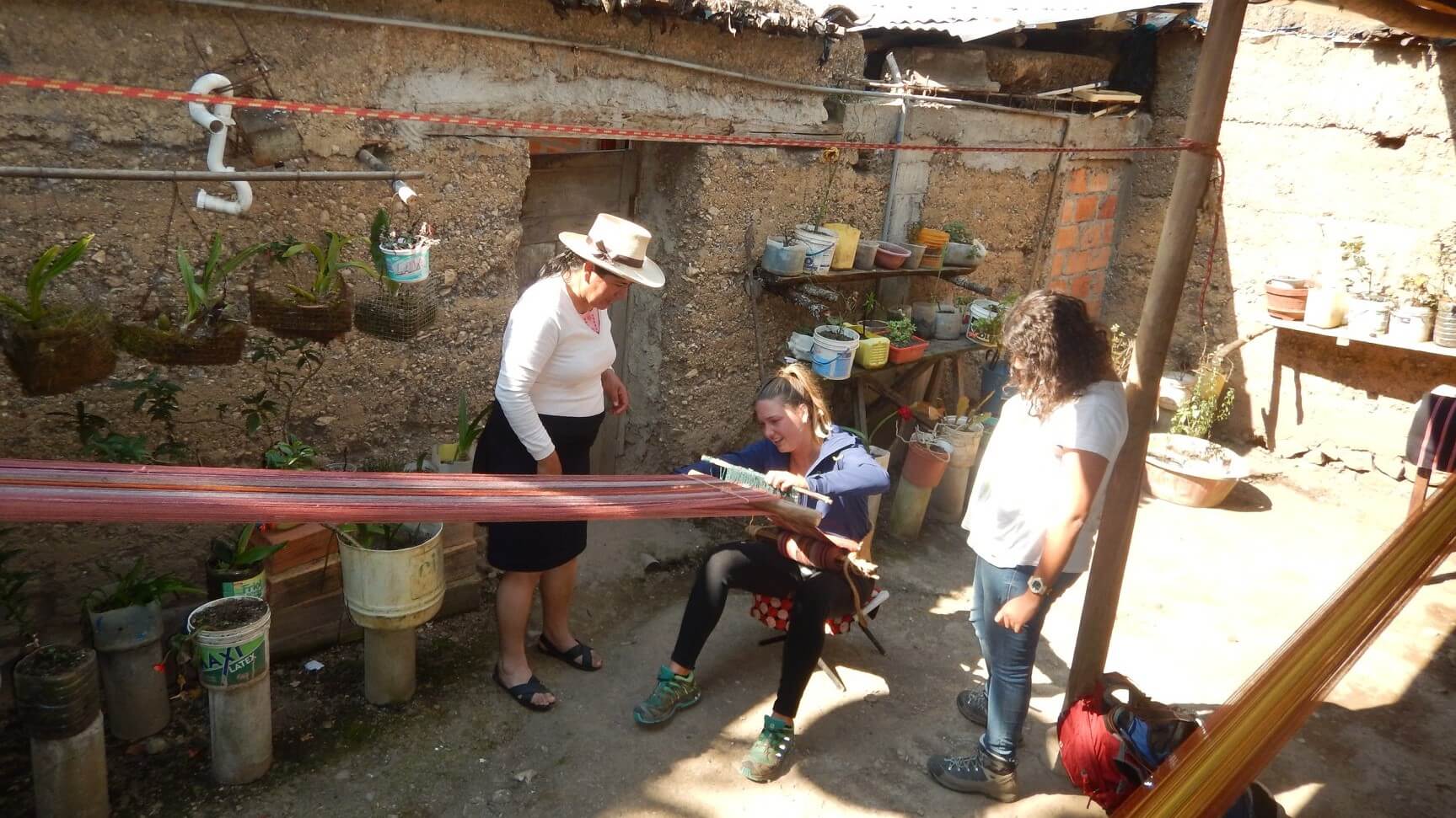 Travelers visiting a craftswoman in her authentic house in Leymebamba, Northern Peru and learning how to weave with a waist loom. Experience the real Peru with Impactful Travel Peru!