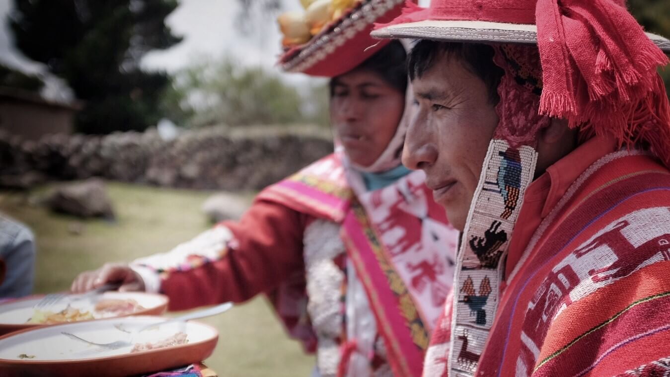 A couple of local inhabitants of the authentic Andean village of Huacahuasi is enjoying lunch with travelers visiting their community. As always, they are wearing beautiful colorful typical garments made of wool. | Community-Based Tourism with RESPONSible Travel Peru