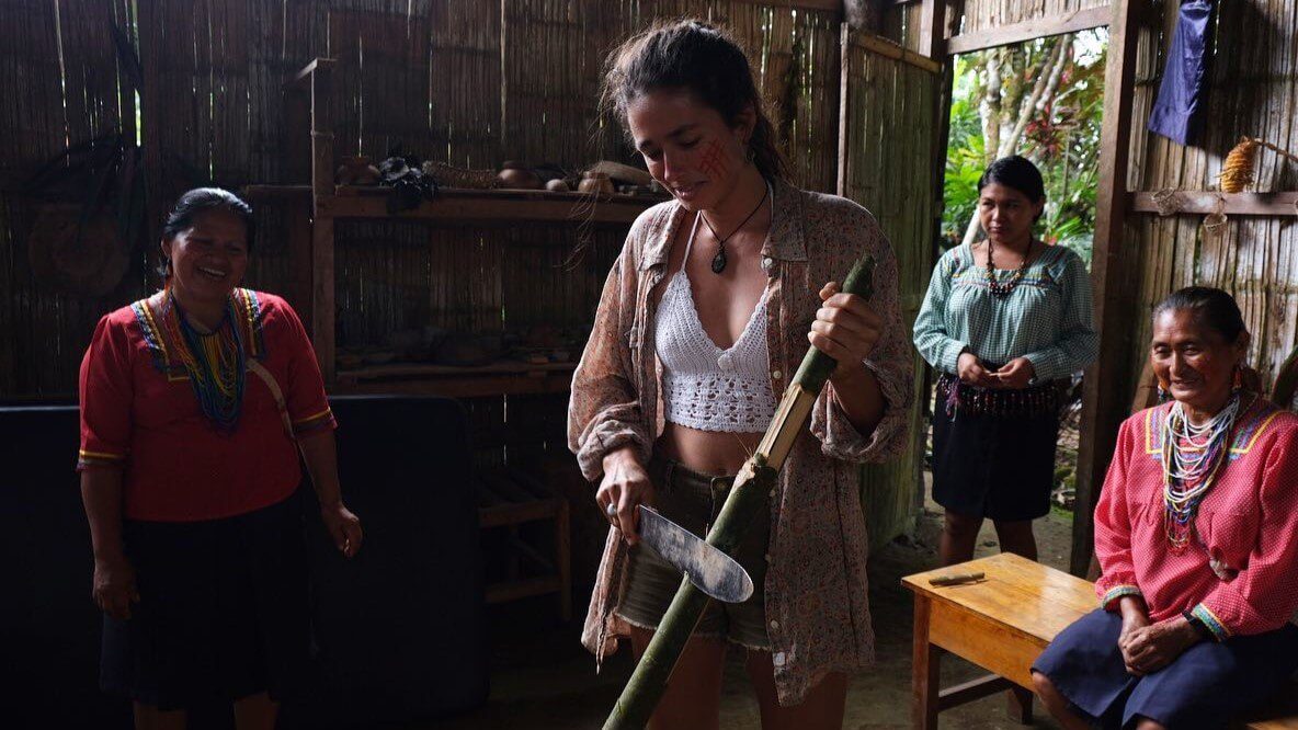 A young woman is practising taking the skin off a bamboo stick with a machete, at Amupakin, Tena, Ecuador. | Impactful Travel