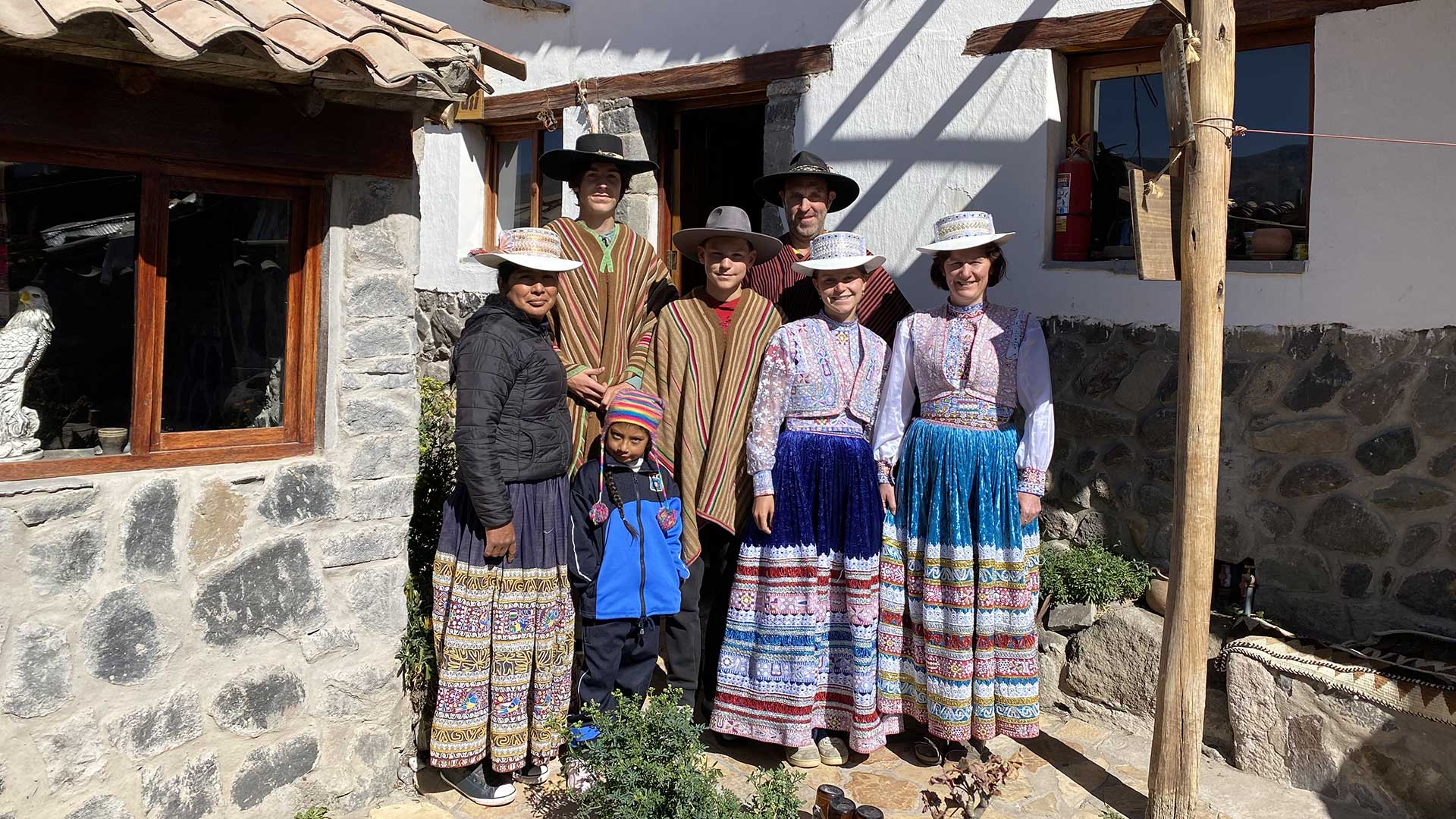 A family from the Netherlands wearing traditional costumes at a rural homestay in Coporaque, Colca, Arequipa, Peru next to their hosts